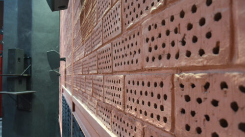 Detailný pohľad na bočnú stenu kino-divadelnej sály realizovanú z netradične kolmo kladených perforovaných keramických tehál
