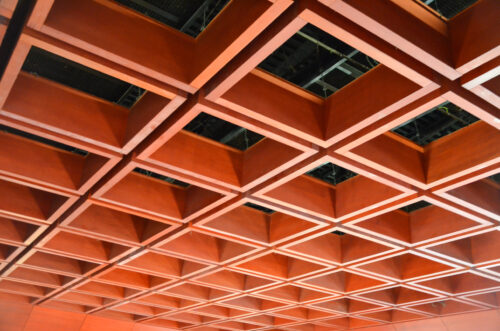 Drevený rastrový podhľad použitý vo viacerých častiach budovy plní funkciu výtvarného dotvorenia, optimalizácie priestorovej akustiky a súčasne prekrytia technických inštalácií