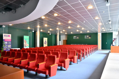 Prednášková sála na 1.np. – v interiéri sály dominuje tmavo-zelená farba obkladových panelov a výrazná červená farebnosť dnes už prečalúnených sedačiek