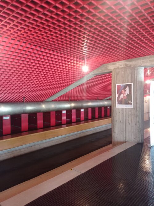 The dressing room section below the sloping auditorium is dominated by a red grid ceiling and a black studded floor