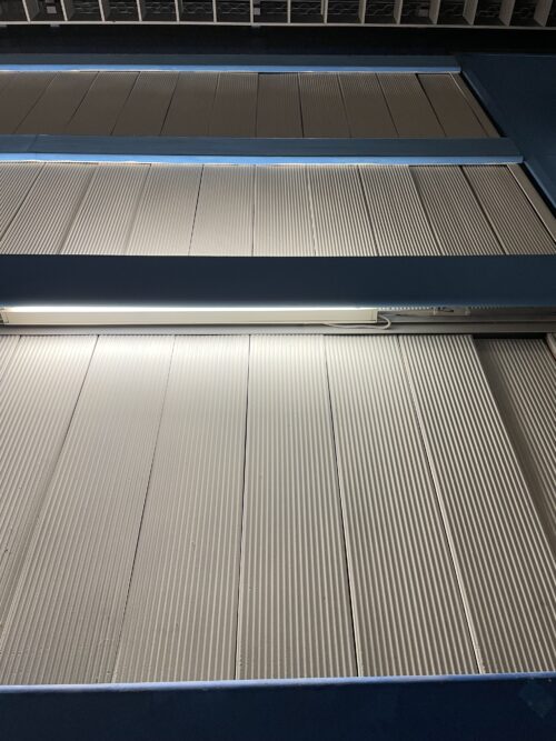 Modrá sála – obklad stien vytvorený kombináciou kanelúrovaných platní a vodorovných kovových profilov slúžiacich na prekrytie lineárnych svietidiel