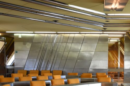 The interior of the meeting hall includes a sculptured stainless steel-based wall