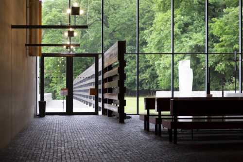 Obradná sieň – drevená stena prechádzajúca z interiéru do exteriéru eliminuje výhľady na dianie v okolí budovy