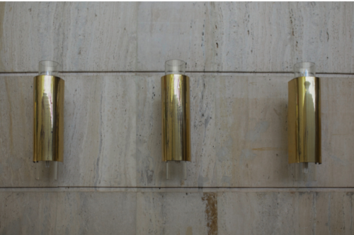 Main building – rhythmically ordered wall lights crown the travertine wall facing in the pre-hall