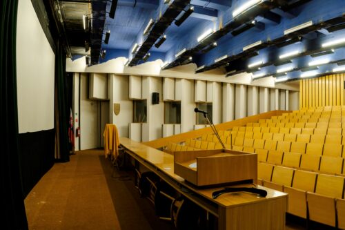 The preserved parts of the conference hall are the sculptured wall panelling, interpretation booths, wooden seating, and the counter section 