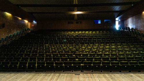 Theatre hall – warm colour palette of the interior is complemented by the olive-green seat upholstery
