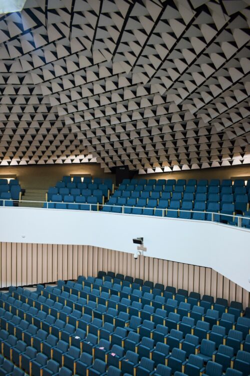 The auditorium, submerged below the ground level, has an amphitheatre-style seating both on the ground floor and on the balcony, with a total capacity of 500 spectators 