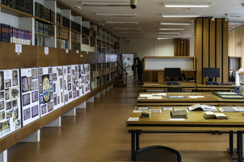 The library tables resembling the building's “rings”, and semi-enclosed study boxes equipped with microfilm reading devices all are a consistent part of the research room