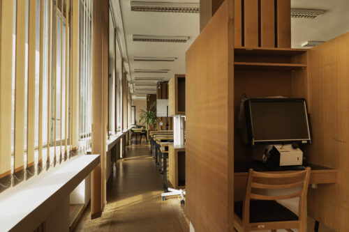 The research room includes semi-enclosed furniture boxes with microfilm reading devices 