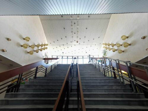 The stairway area is decorated by sets of walls and ceiling-hung luminaires