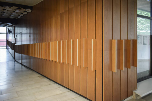 The corner of the ramp, where the respirium and the corridor to the lecture halls meet, is complemented by lamellar panelling with clearly visible vertical lines 