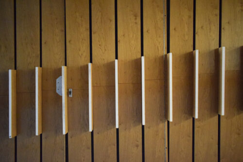 Lamelový obklad s vystupujúcimi drevenými platňami v sebe „ukrýva“ vstup do technického zázemia